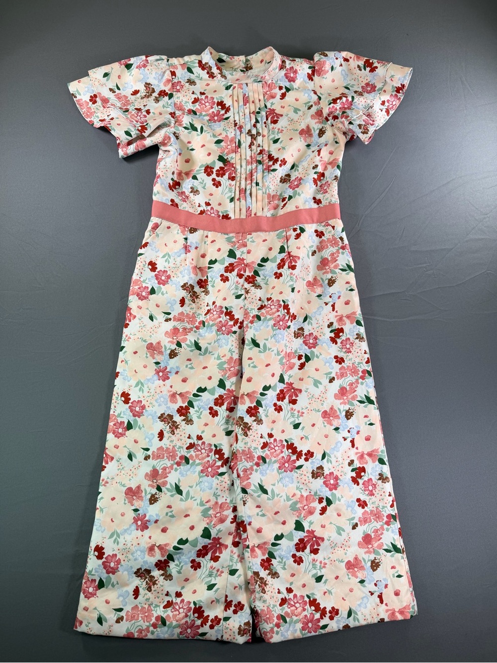 Janie and Jack floral ruffle sleeve jumpsuit with a pink waistband.